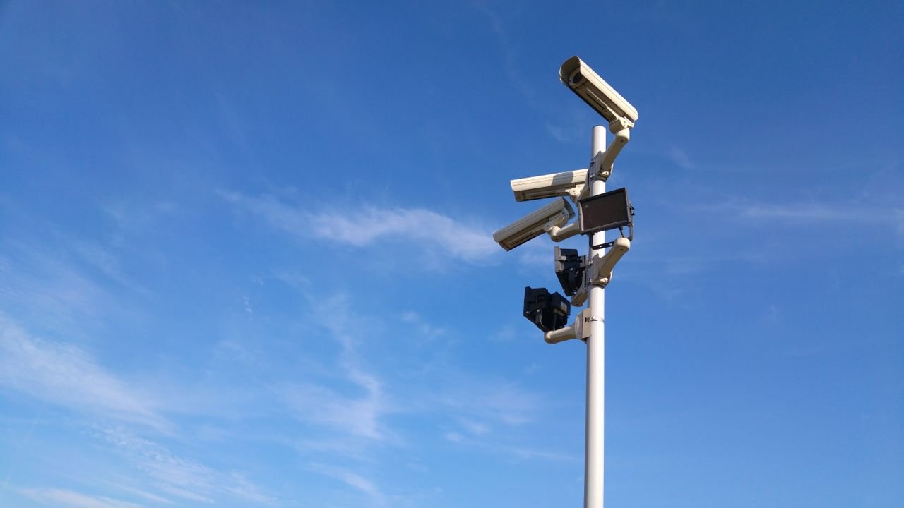 Services-03 Multiple security cameras on a pole with a clear blue sky backdrop.