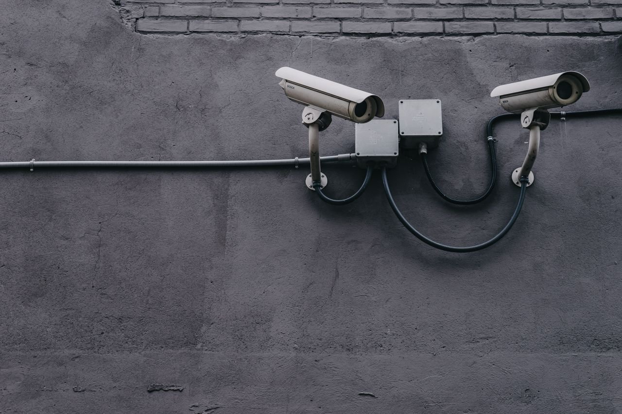 Services-02 Two surveillance cameras mounted on a concrete wall, highlighting security technology.
