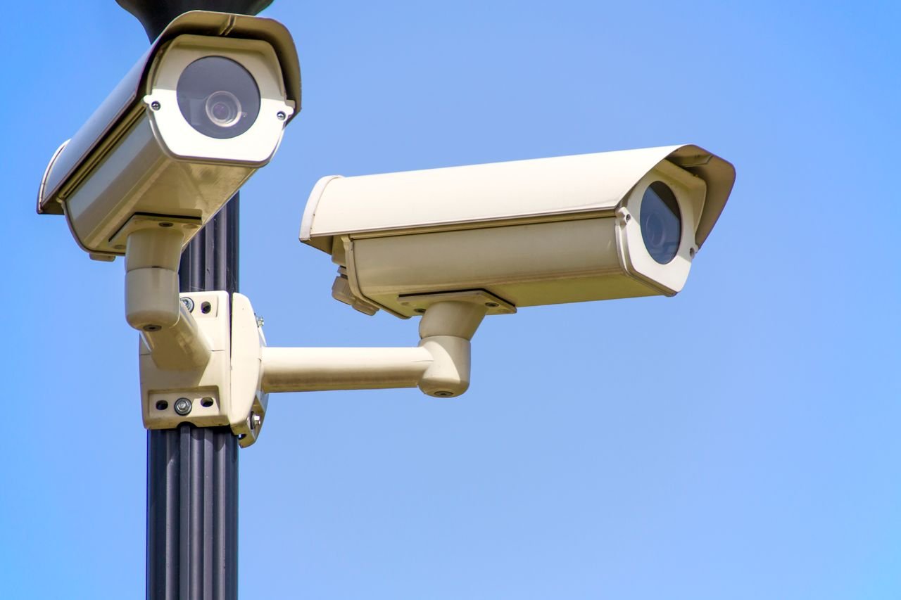creative Outdoor security cameras mounted on a pole against a clear blue sky, ensuring vigilant surveillance.